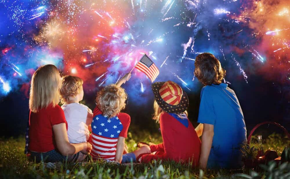 American family celebrating Independence Day. Picnic and fireworks on 4th of July in America. USA flag. Parents and kids celebrate US holiday. Children watching firework.